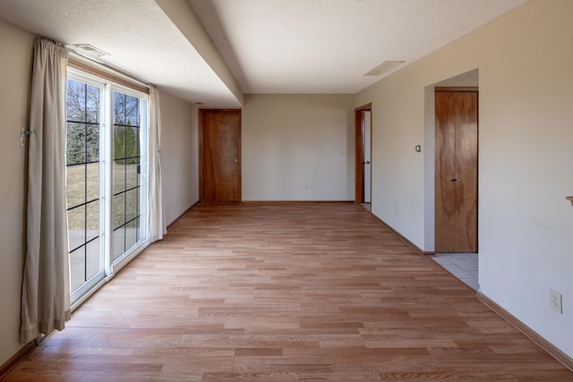 unfurnished room featuring light wood finished floors, a wealth of natural light, and a textured ceiling