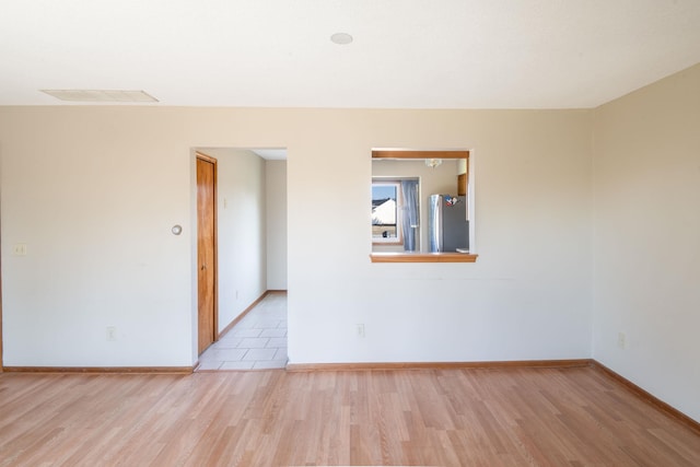 spare room featuring visible vents, baseboards, and wood finished floors