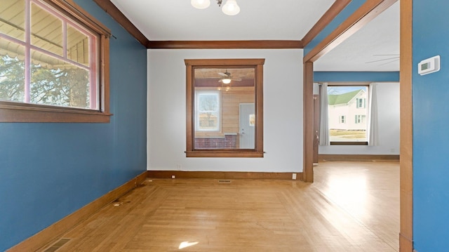 spare room with wood finished floors, visible vents, a wealth of natural light, and baseboards