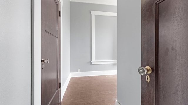 hallway featuring baseboards and wood finished floors