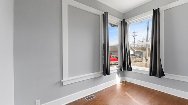 unfurnished room featuring dark wood-style floors, visible vents, and baseboards