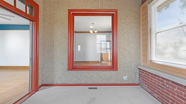 unfurnished room with a wealth of natural light, a notable chandelier, wallpapered walls, and baseboards