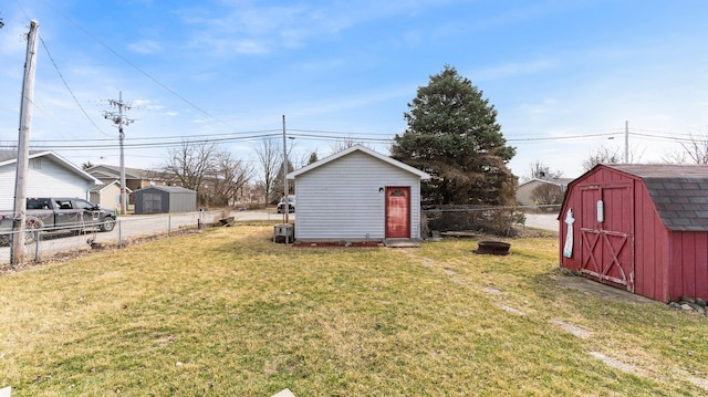 view of yard featuring a storage unit, an outbuilding, and fence