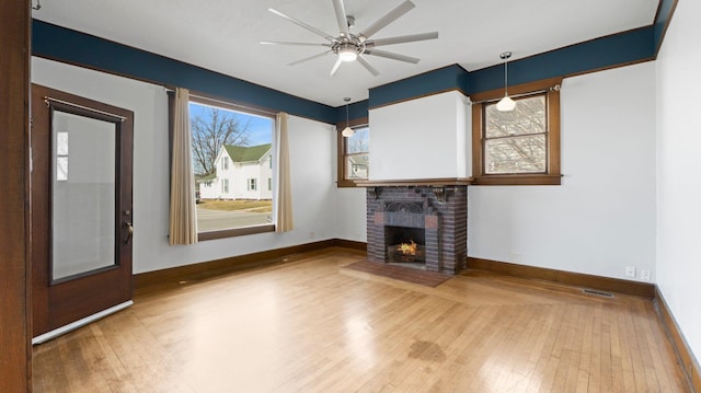 unfurnished living room featuring plenty of natural light, wood-type flooring, and ceiling fan