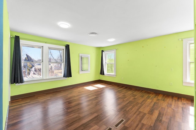 spare room with visible vents, baseboards, and dark wood-style flooring