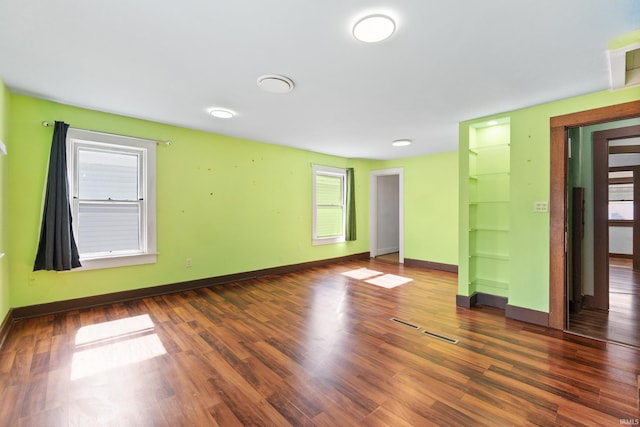 unfurnished room with baseboards and dark wood-style floors