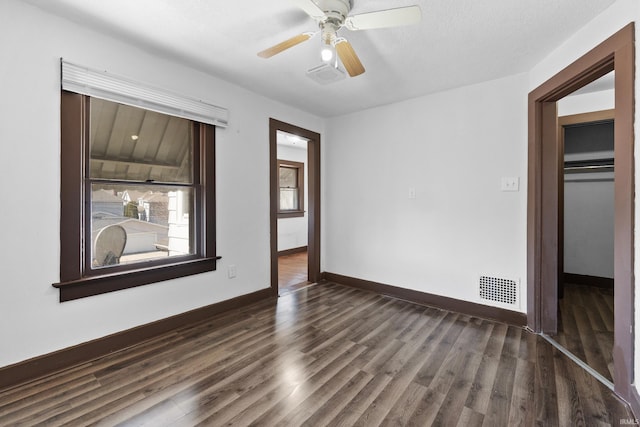 unfurnished room with visible vents, baseboards, dark wood-type flooring, and ceiling fan