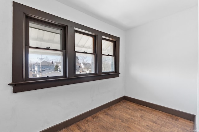 unfurnished room with baseboards and dark wood-style floors