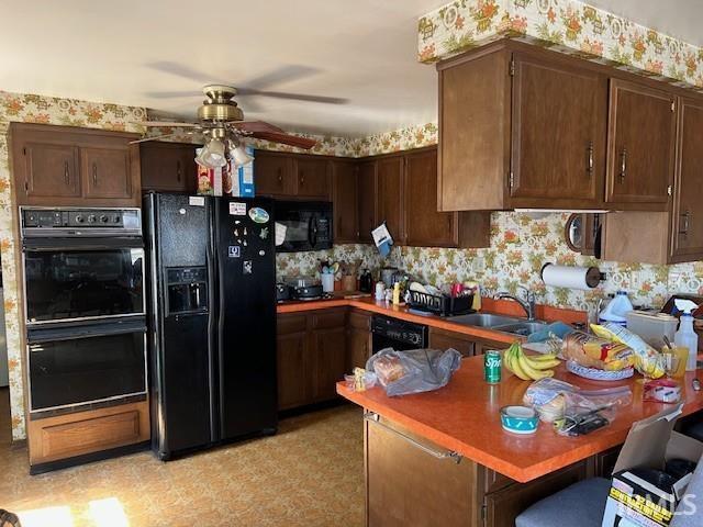 kitchen with black appliances, a sink, a peninsula, dark brown cabinets, and ceiling fan