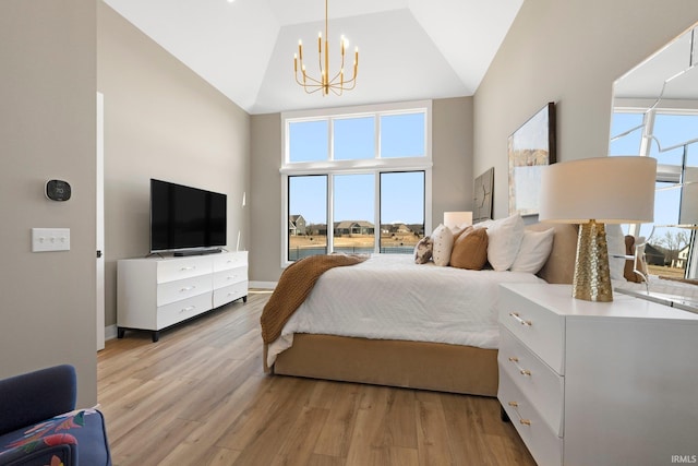 bedroom featuring a notable chandelier, light wood-style flooring, and high vaulted ceiling