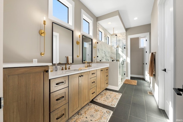 full bath featuring a sink, a marble finish shower, double vanity, and tile patterned floors