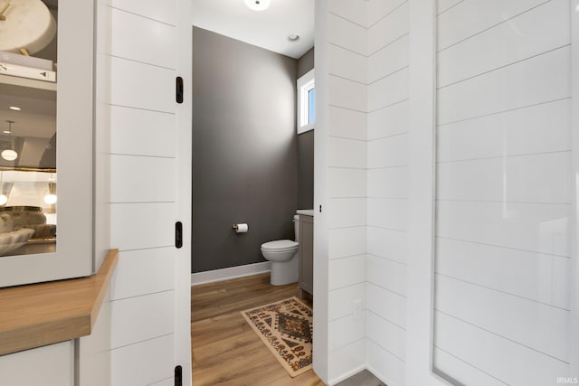 bathroom with baseboards, toilet, and wood finished floors