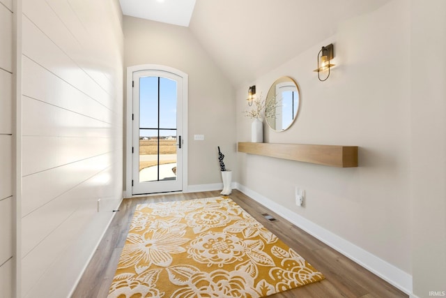 doorway to outside with lofted ceiling with skylight, wood finished floors, and baseboards