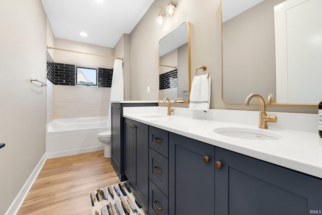 bathroom with a sink, baseboards, wood finished floors, and double vanity