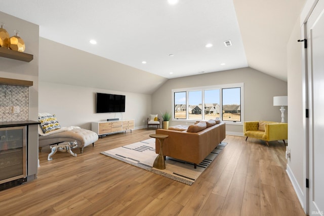 living room featuring visible vents, baseboards, lofted ceiling, recessed lighting, and light wood-style floors