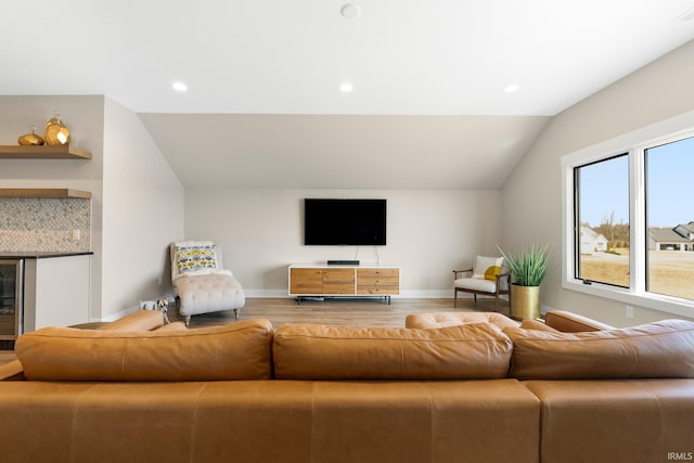 living area with recessed lighting, wood finished floors, baseboards, and vaulted ceiling