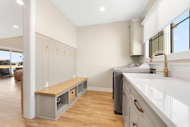 clothes washing area with independent washer and dryer, light wood-style flooring, recessed lighting, cabinet space, and baseboards