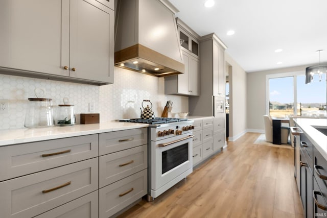 kitchen featuring high end white range oven, premium range hood, and gray cabinetry