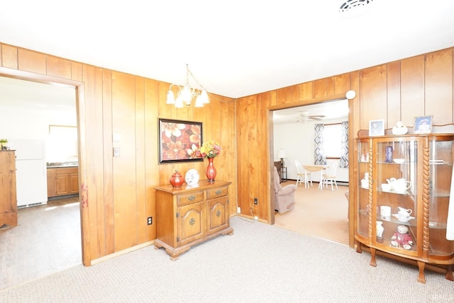 hall featuring wooden walls, a notable chandelier, and light carpet