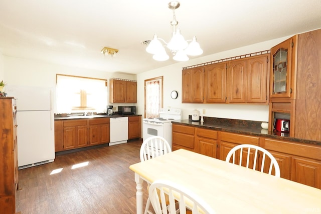 kitchen featuring brown cabinets, a sink, wood finished floors, white appliances, and a chandelier