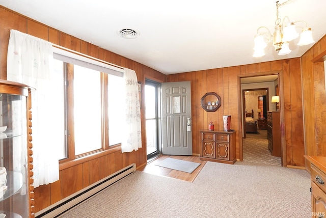 carpeted entryway featuring a baseboard heating unit, an inviting chandelier, wood walls, and visible vents