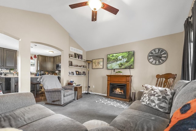 living area with carpet, visible vents, arched walkways, ceiling fan, and a glass covered fireplace