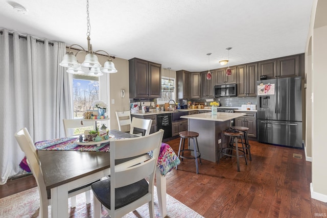 dining area with baseboards, dark wood-type flooring, a healthy amount of sunlight, and a chandelier