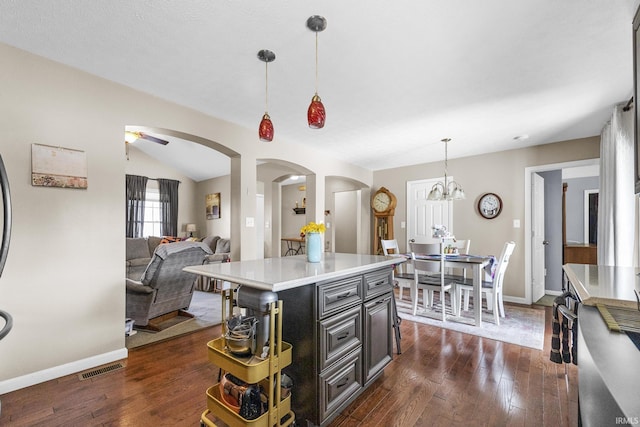 kitchen with arched walkways, pendant lighting, dark wood-style flooring, and light countertops