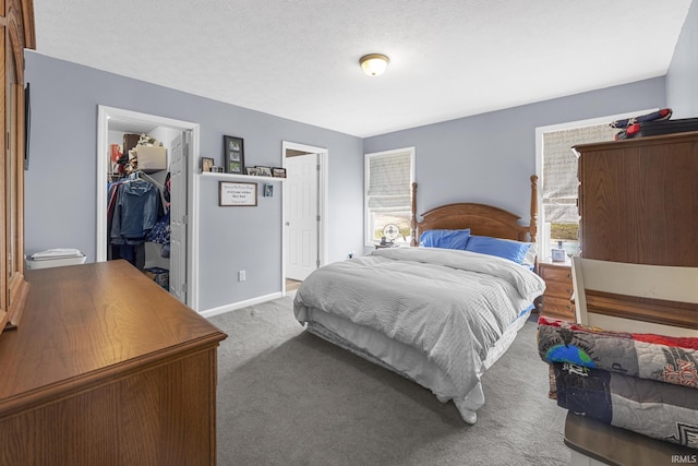 bedroom featuring a spacious closet, baseboards, carpet flooring, a closet, and a textured ceiling