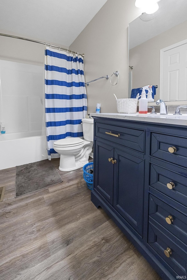 bathroom featuring vanity, toilet, wood finished floors, and shower / bath combo