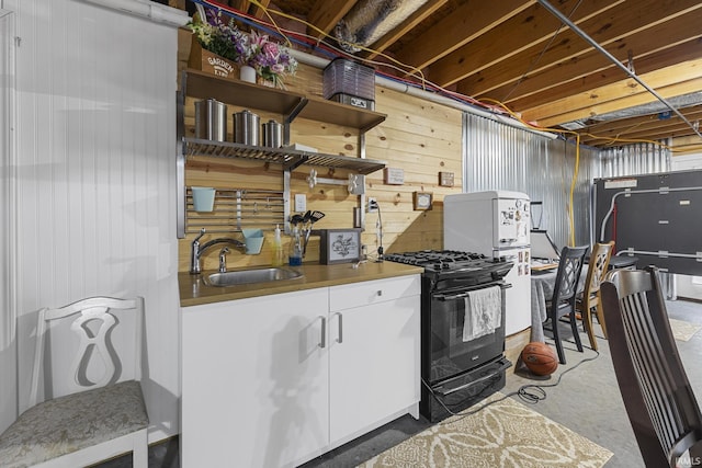 kitchen featuring a sink, open shelves, black gas range, white cabinetry, and unfinished concrete floors