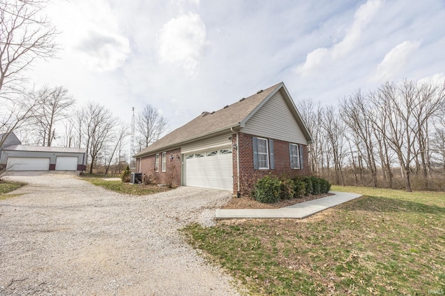 view of property exterior featuring an outbuilding, driveway, roof with shingles, an attached garage, and brick siding