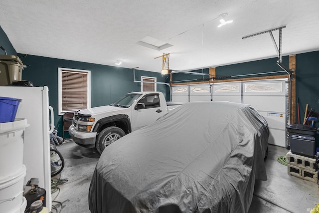 garage featuring a garage door opener and freestanding refrigerator