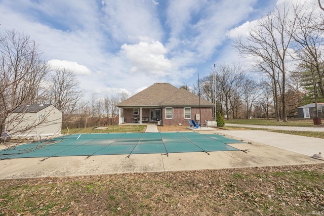 view of pool featuring a covered pool, a shed, a patio, and an outdoor structure