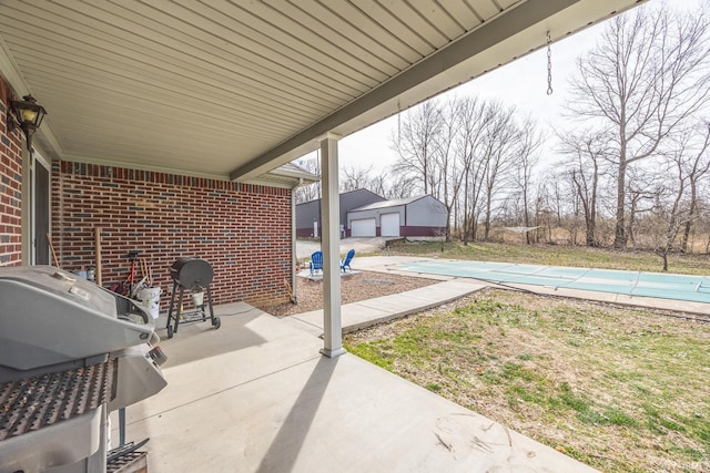 view of patio with grilling area, an outdoor structure, and a covered pool