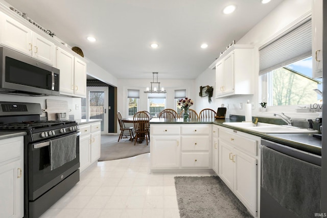 kitchen featuring black gas range oven, stainless steel microwave, dishwashing machine, a peninsula, and a sink