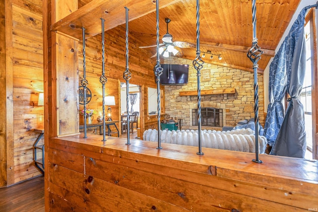 unfurnished living room featuring wooden walls, a ceiling fan, wood finished floors, lofted ceiling with beams, and wood ceiling