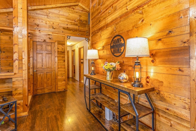 hallway with wood finished floors, wood walls, and high vaulted ceiling