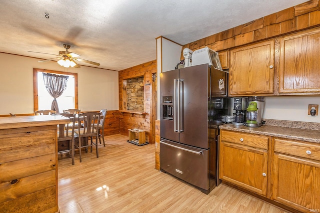 kitchen with a ceiling fan, light wood-style flooring, brown cabinetry, and high end refrigerator