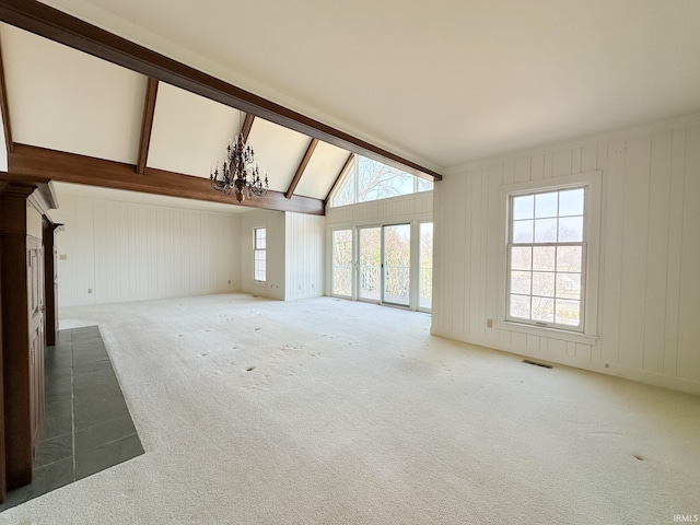 carpeted spare room featuring a chandelier, visible vents, plenty of natural light, and lofted ceiling with beams