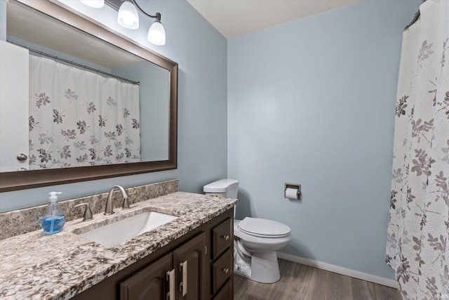 full bath with baseboards, toilet, wood finished floors, and vanity