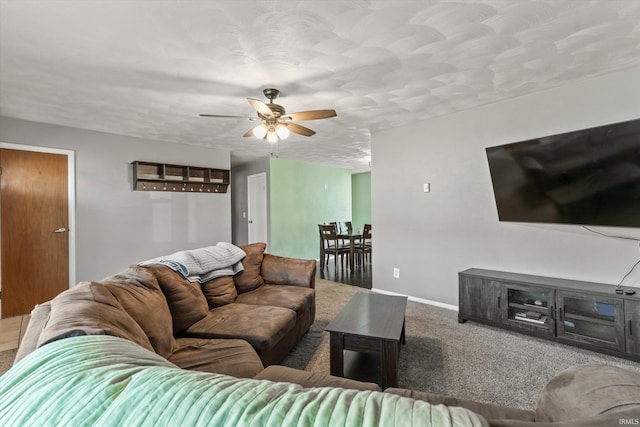 carpeted living area featuring a textured ceiling, baseboards, and ceiling fan