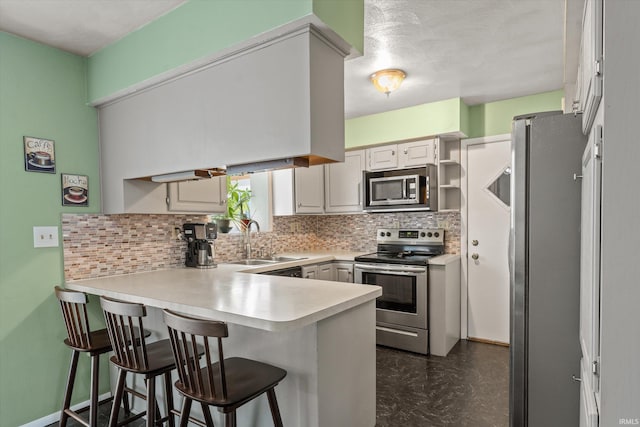 kitchen with a sink, decorative backsplash, a peninsula, stainless steel appliances, and open shelves