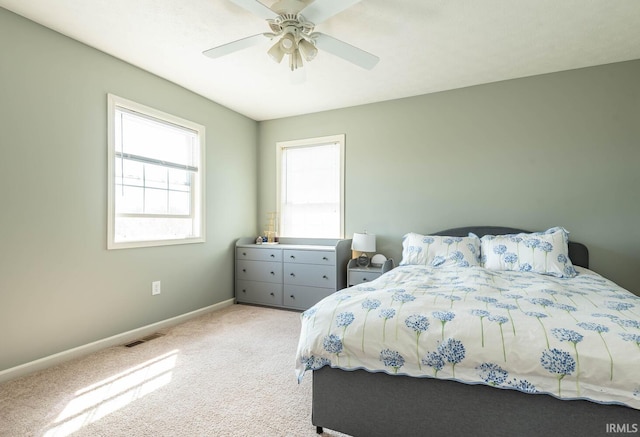 bedroom with visible vents, baseboards, light colored carpet, and ceiling fan