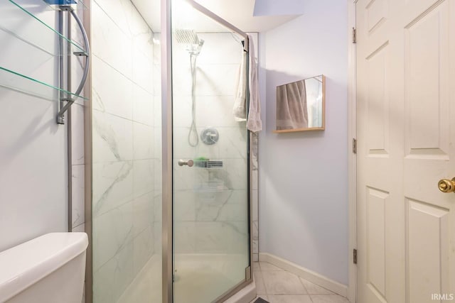 bathroom featuring tile patterned flooring, toilet, baseboards, and a stall shower