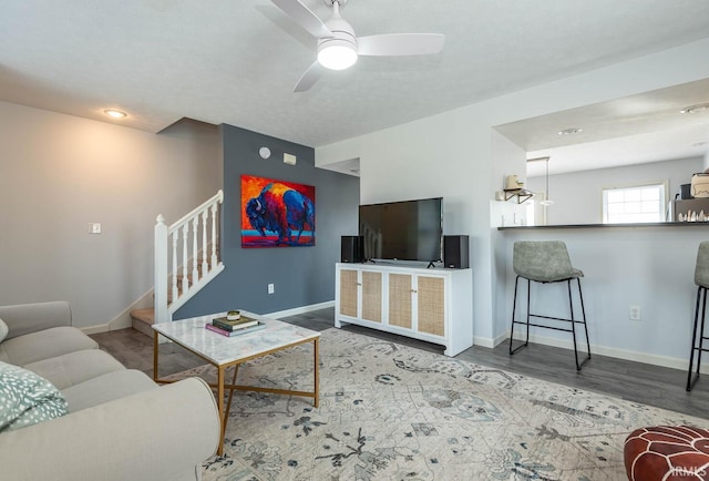 living room with ceiling fan, baseboards, and wood finished floors