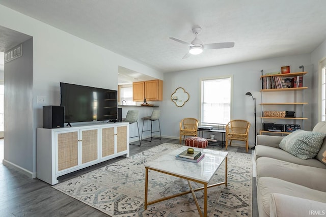 living area featuring baseboards, wood finished floors, visible vents, and ceiling fan