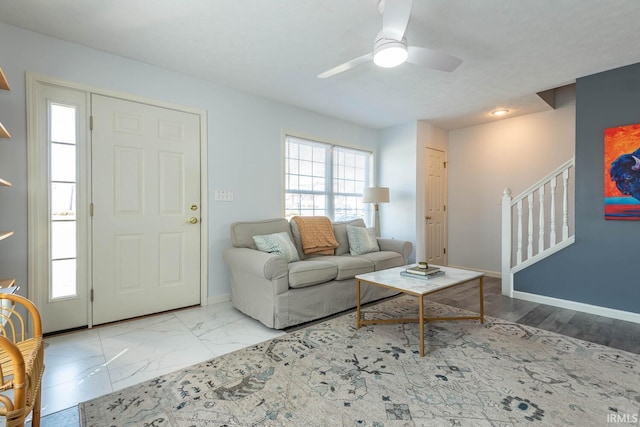 living area with stairway, baseboards, marble finish floor, and ceiling fan