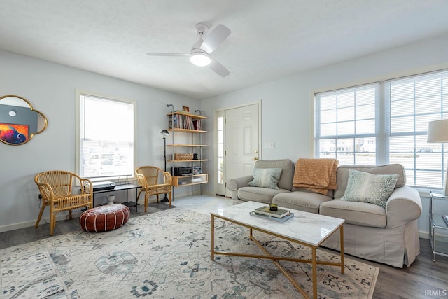 living room featuring baseboards, ceiling fan, and wood finished floors