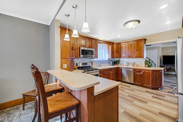 kitchen with stainless steel appliances, a peninsula, a breakfast bar area, light countertops, and decorative backsplash